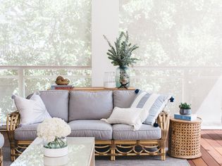 Outdoor living room decorated with brown wicker and gray couch, throw pillows and houseplants