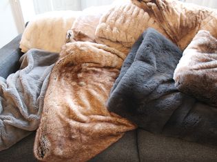 Several faux fur blankets displayed on a sofa