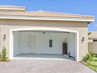 garage and driveway of light beige home with the garage door open and inside empty