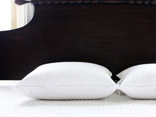 Parachute Down Pillows displayed on bed with ornate wood headboard