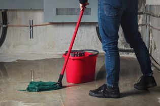 Person cleaning up a damp basement floor