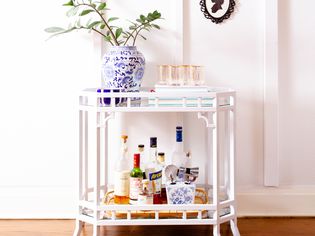 White mini bar decorative vase and cups above liquor bottles
