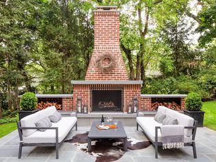 Backyard patio with brick fireplace and brown and white cowhide rug 
