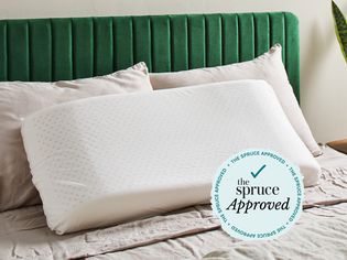 A latex pillow resting on two other pillows on a bed with a The Spruce Approved badge.