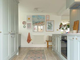 light blue small galley kitchen with pastel gallery wall