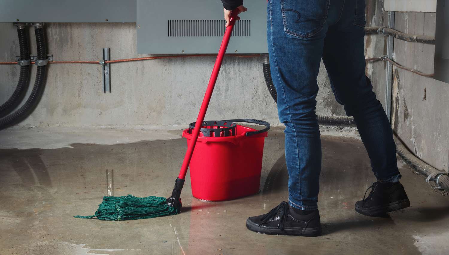 Person cleaning up a damp basement floor
