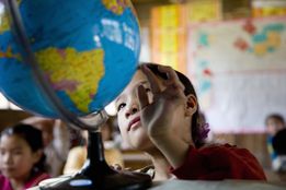 Girl looking at a globe in a classroom.