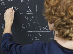 High School Student Solving Equation on Blackboard