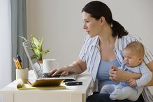 woman working on laptop with baby in her lap