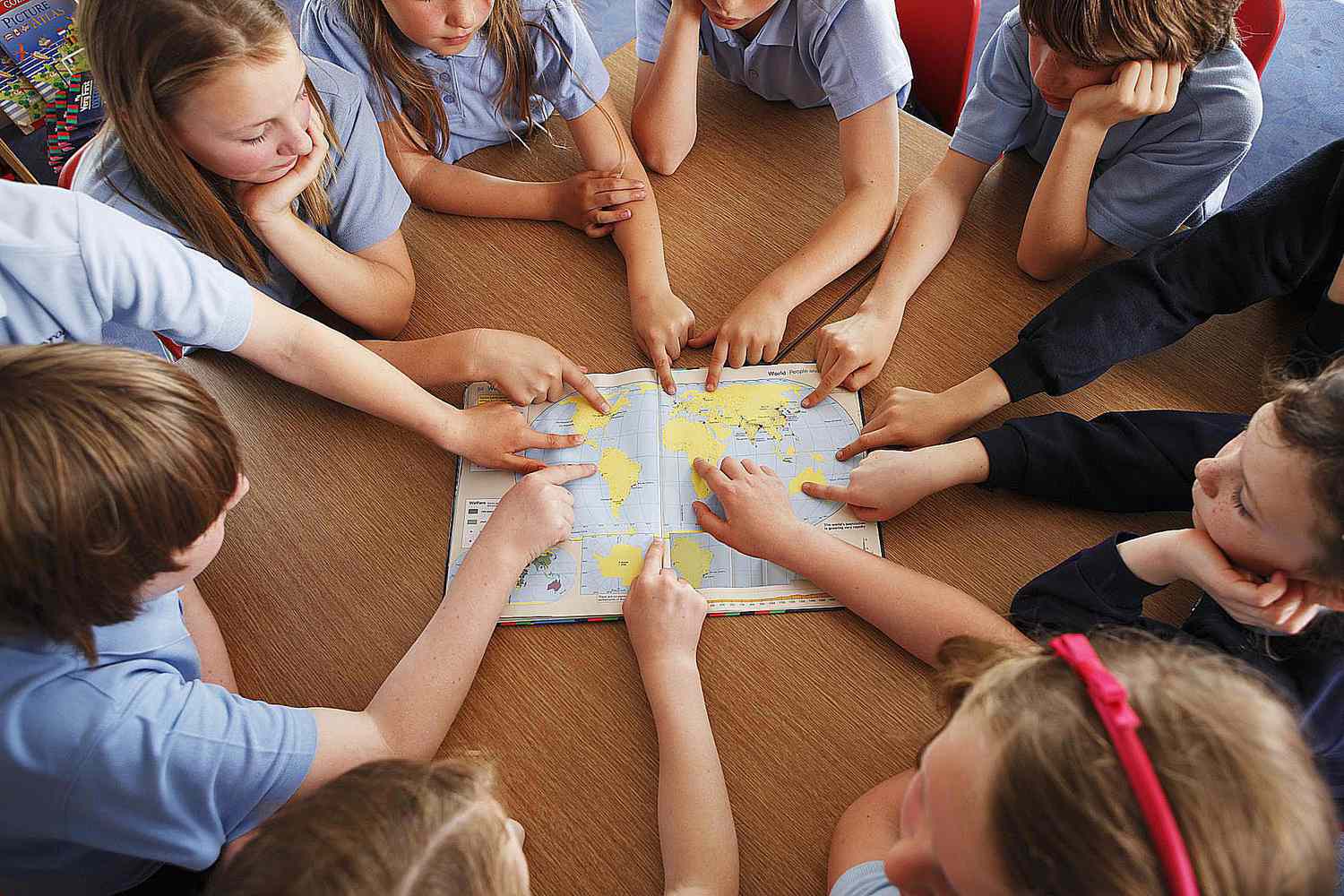 Group of schoolchildren using atlas together