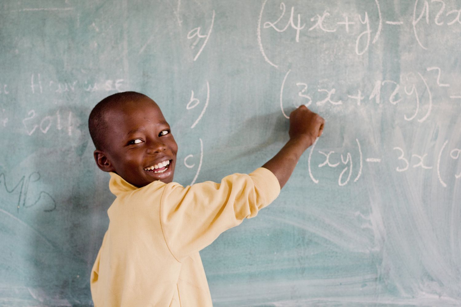 Smiling boy writing on blackboard