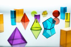 Group of various multi colored geometric shapes resting on a mirror