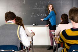 Student solving a tenth grade math problem on a classroom chalkboard
