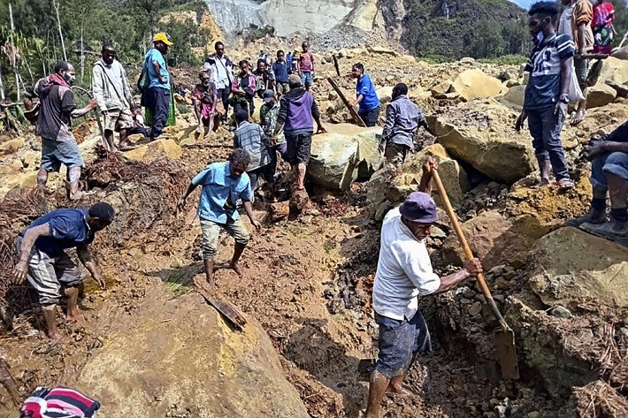 ２６日、パプアニューギニアで、地滑りが起きた現場を捜索する人々＝ＡＰ