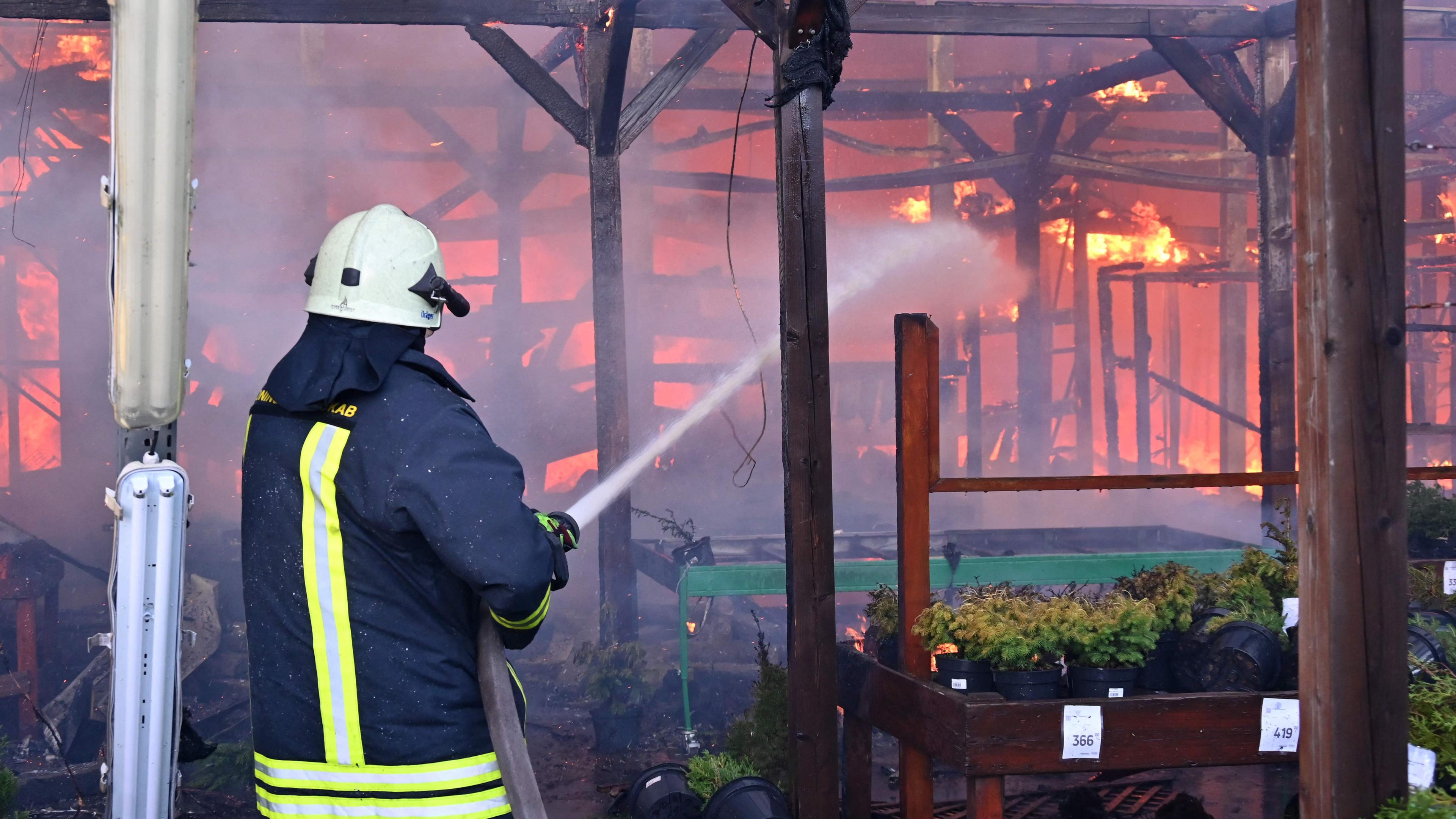 Ein ukrainischer Feuerwehrmann löscht in Charkiw einen Brand in einem Baumarkt nach einem russischen Angriff.