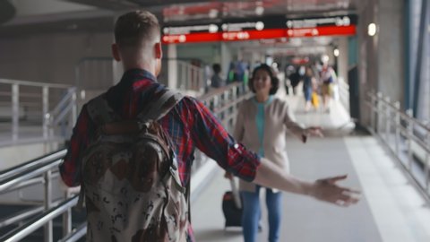 Young hipster man meeting his senior mother in airport walkway. They are greeting each other and hugging. Happy reunion of aged woman and her adult son. - Βίντεο στοκ