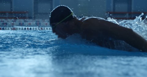 A professional swimmer raising a lot of splashes is swimming in butterfly style along his path in the pool. Slow mo, slo mo, slow motion, high speed camera Arkivvideo