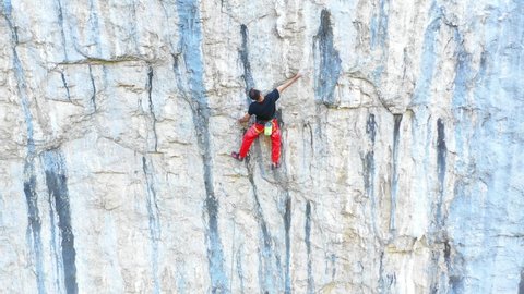 Young fit man climbing on very steep mountain cliff, outdoors rock climbing and active lifestyle concept. Camera movement reveals the mountain wall cliff. Extreme sports concept. Rocky Mountains. 스톡 비디오