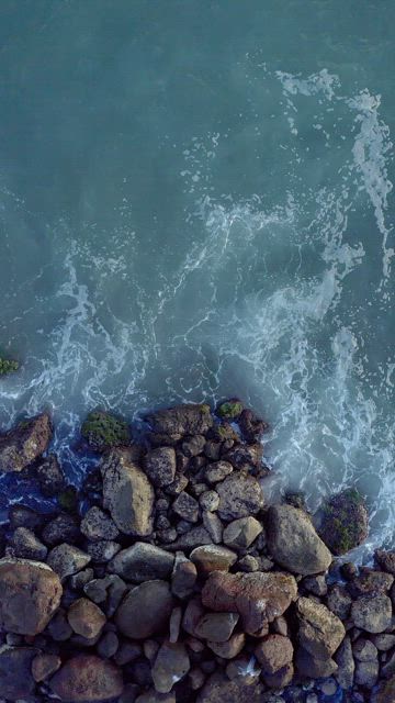 Overhead view of a rocky coast and waves crashing.