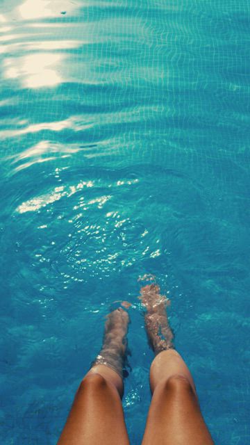 Woman's feet splashing in the pool .