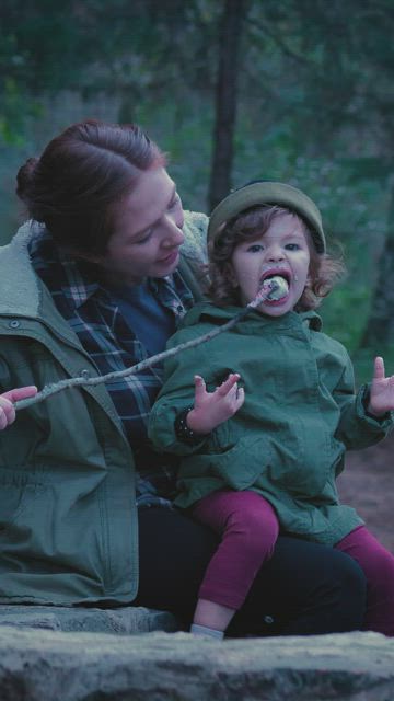 Mother with her little daughter eating a marshmallow in nature.