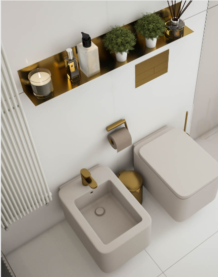 Elegant Westchester, NY bathroom renovation showcasing a white wall-hung toilet, matching bidet, and gold accent shelf with greenery and luxury toiletries.