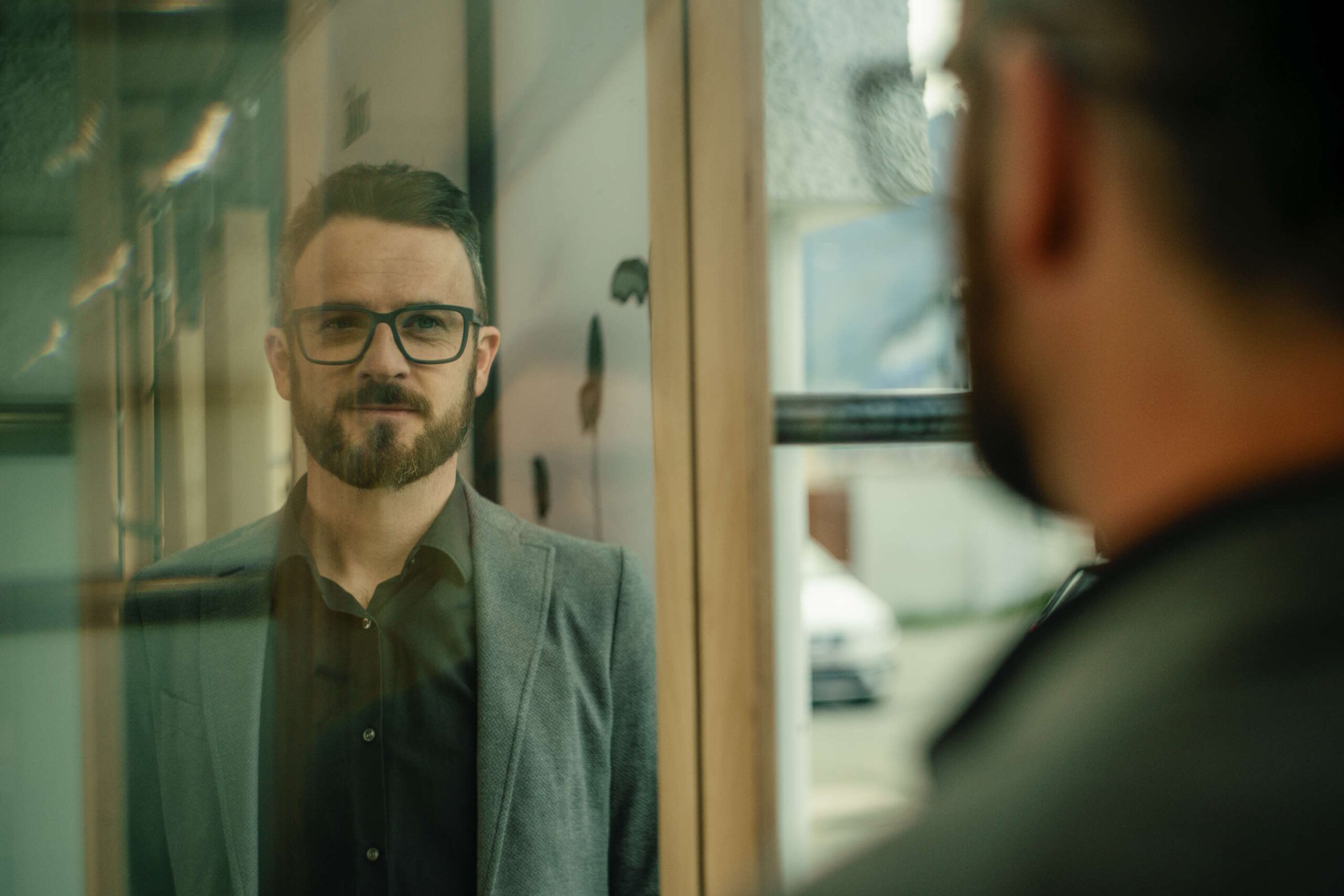 Mann mit Brille und Bart, der in einem Spiegel schaut, zeigt wellenartiges Flimmern im Auge