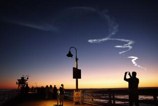 SAN CLEMENTE, CALIFORNIA - APRIL 01: People walk on a pier beneath the contrail from a SpaceX Falcon 9 rocket carrying a payload of 22 Starlink internet satellites into space after launching from Vandenberg Space Force Base on April 1, 2024 in San Clemente, California. The launch was visible across much of Southern California. (Photo by Mario Tama/Getty Images)