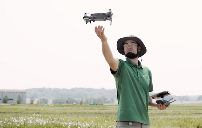 صورة لرجل يستخدم طائرة بدون طيار في أحد الحقول.