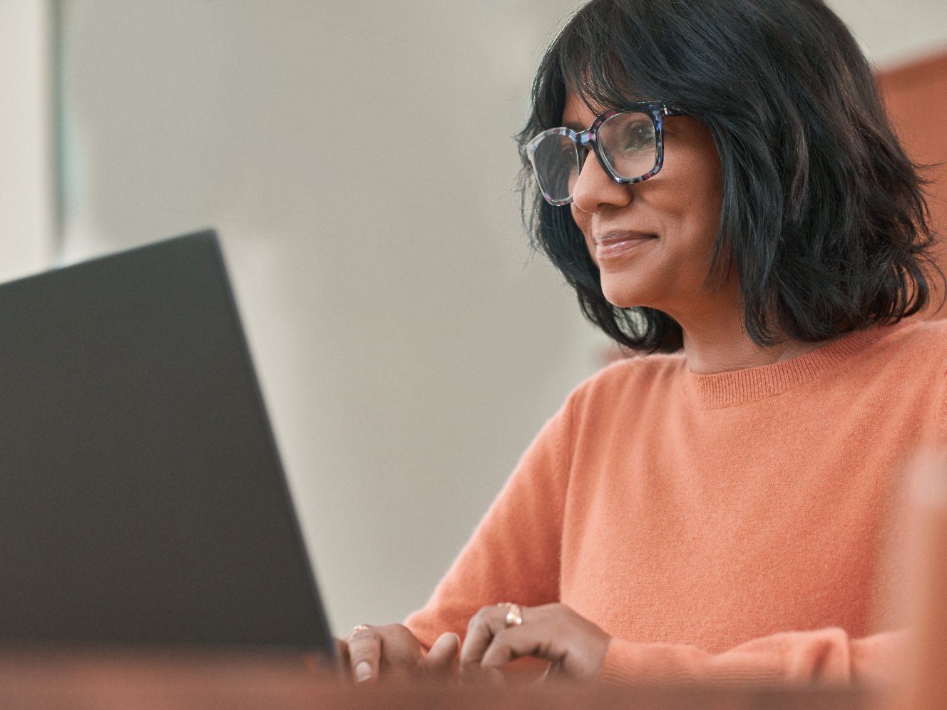Silmälasipäinen nainen työskentelee kannettavalla tietokoneella