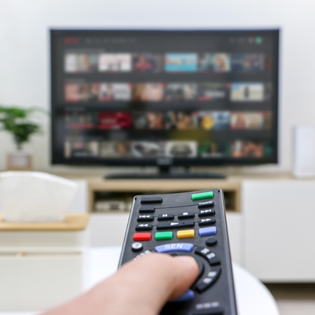 A remote is pointed toward a TV with Netflix on.