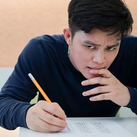 High school student frowns and feeling stressed after reading question about SAT test examination in a classroom (testing, education, teenager)