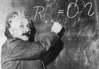 Albert Einstein at the blackboard writing an equation with chalk.