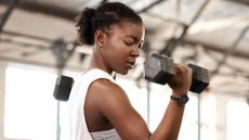Woman doing bicep curl in a gym with dumbbell