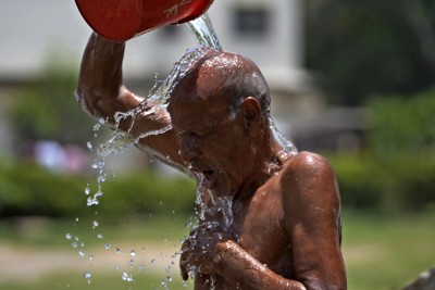 熱波に見舞われたパキスタンで頭から水をかけて涼を取る男性＝カラチで2024年5月21日、AP