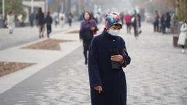 Женщина в маске с кошельком стоит на улице