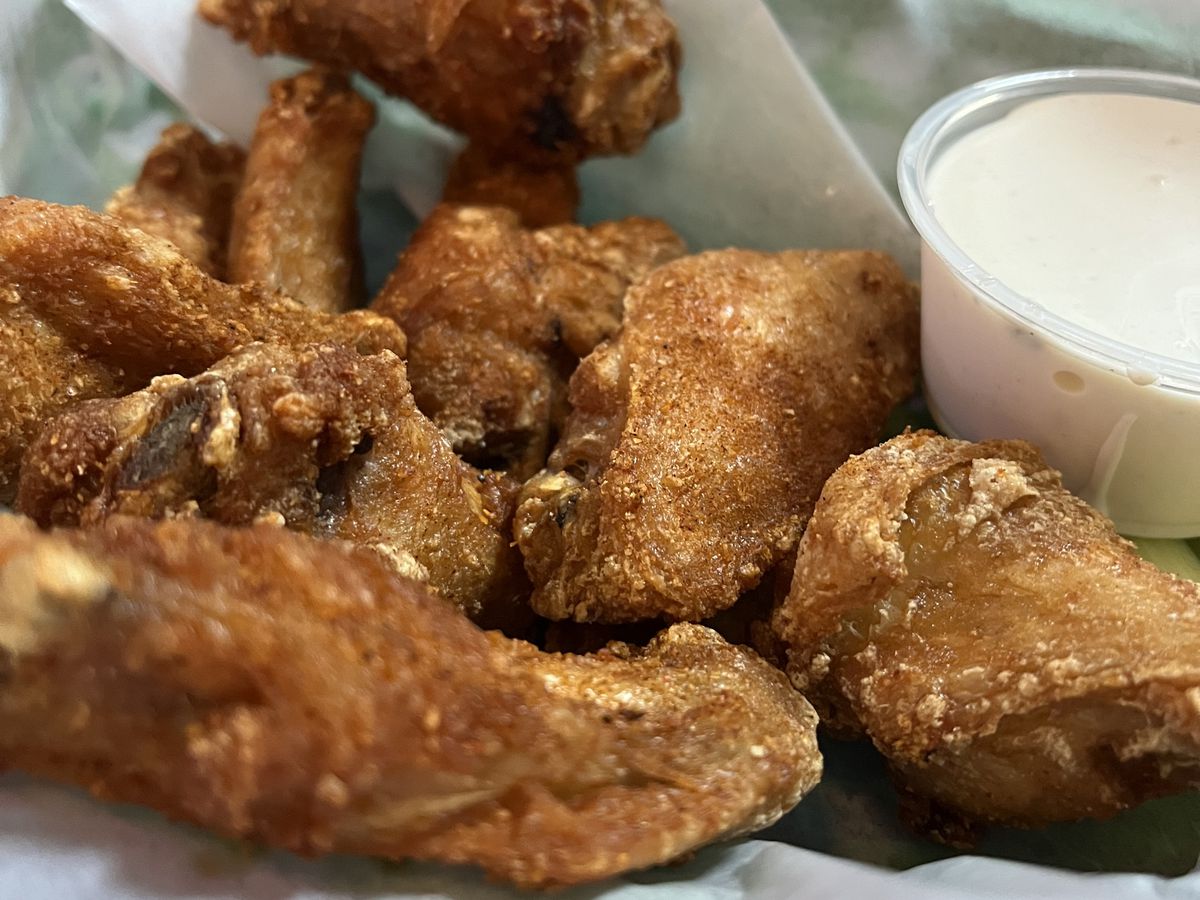 Fried chicken wings in a paper-lined basket with dipping sauce.