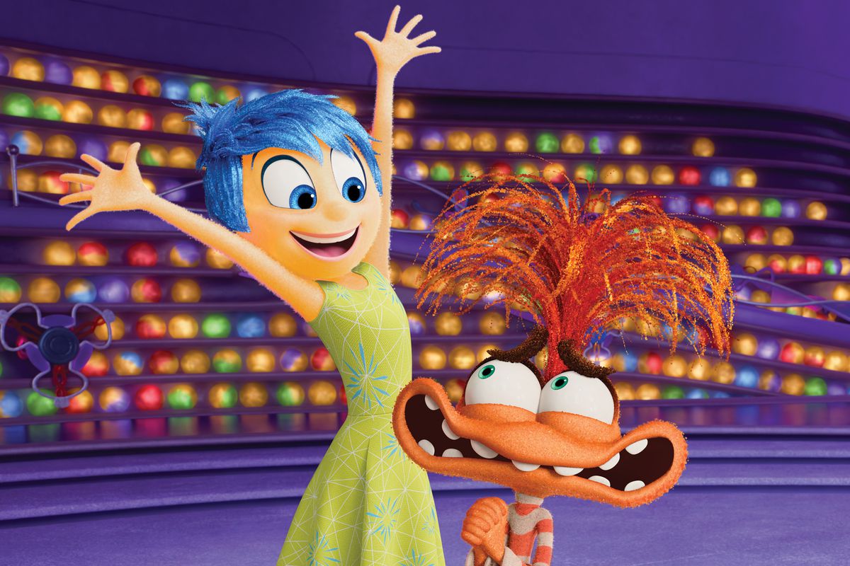 Joy, a yellow figure, throws her hands up as she greets Anxiety, an orange muppet-like figure, in Inside Out 2