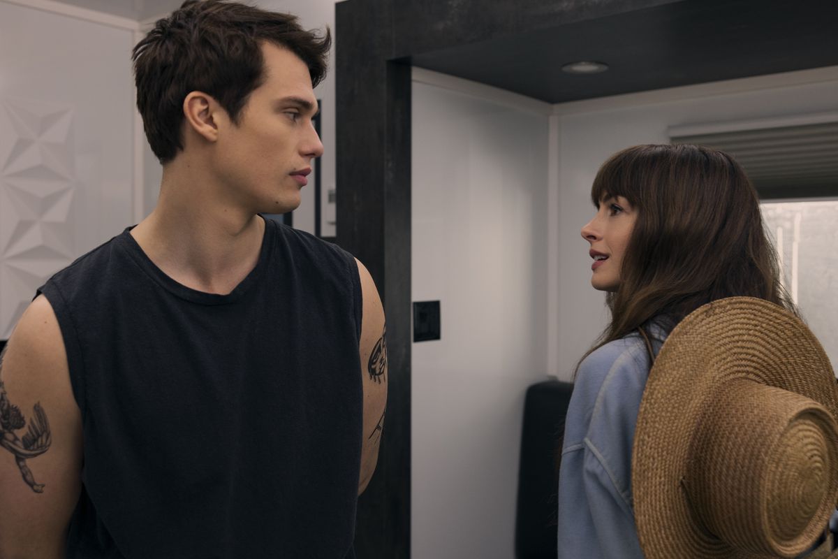 Anne Hathaway, with a big hat on her back, and Nicholas Galitzine, dressed like a pop star, stare longingly at each other in The Idea of You.