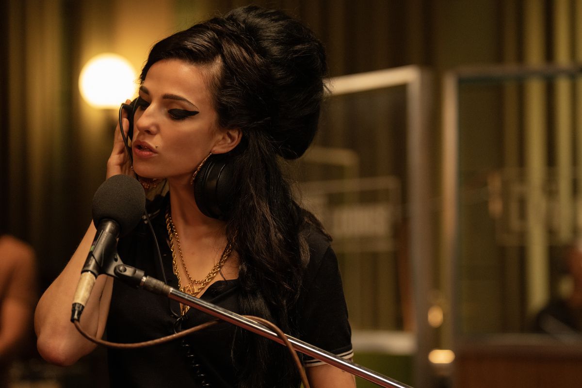 Marisa Abela as Amy Winehouse sings into a microphone in a recording studio in Back to Black