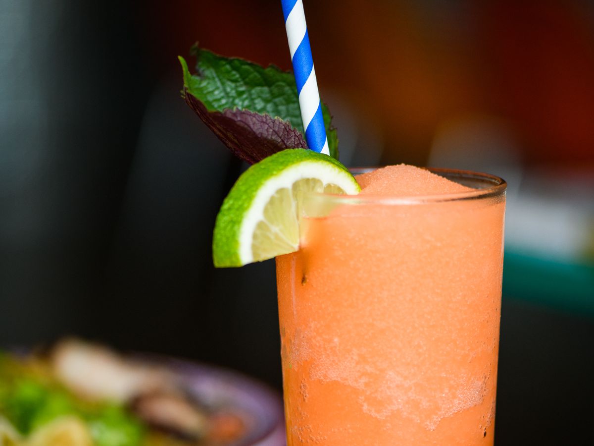 An orange slushie, garnished with a lime, sits on a red table at Oma’s Hideaway. The Moonage Daydream Slushie is made with tequila, pineapple, and mint.
