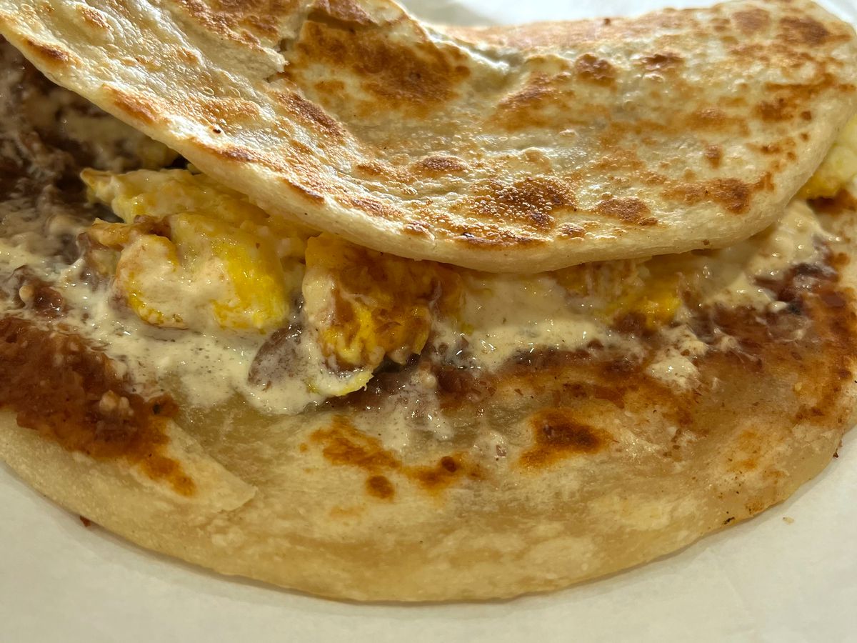 A baleada, with eggs, beans, and other filings poking out.