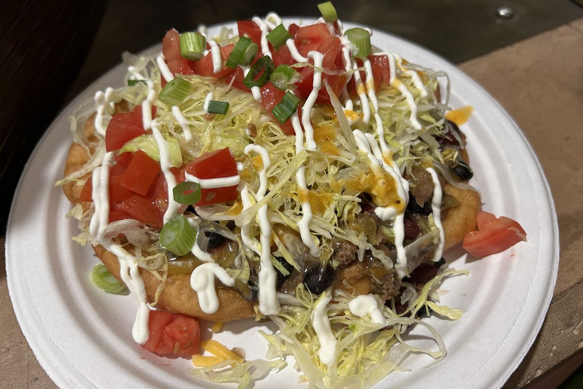Frybread topped with chili, lettuce, tomato, and a drizzle of sour cream.