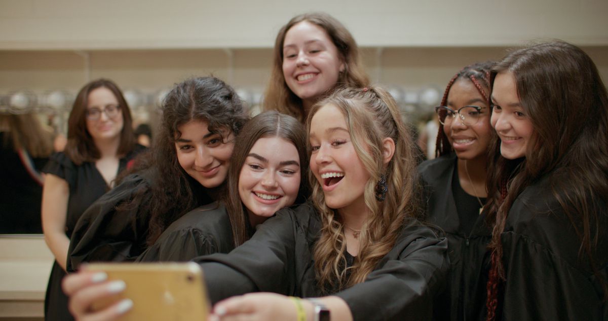 A group of teenage girls pose for a selfie while wearing black robes in the documentary Girls State