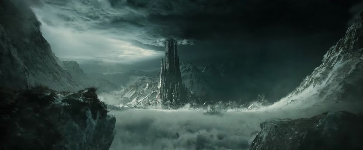 A black, jagged tower reaches upwards to grey clouds at the bottom of a valley in the trailer for season 2 of The Lord of the Rings: The Rings of Power