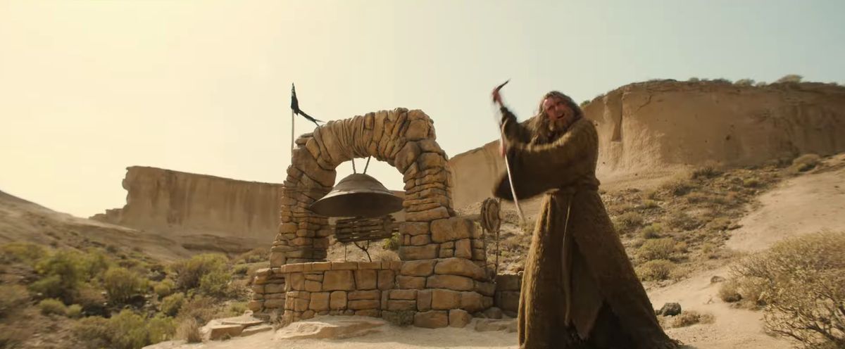 The Stranger waves his staff in a desert-like environment, with some kind of bell or well behind him in the trailer for season 2 of The Lord of the Rings: The Rings of Power