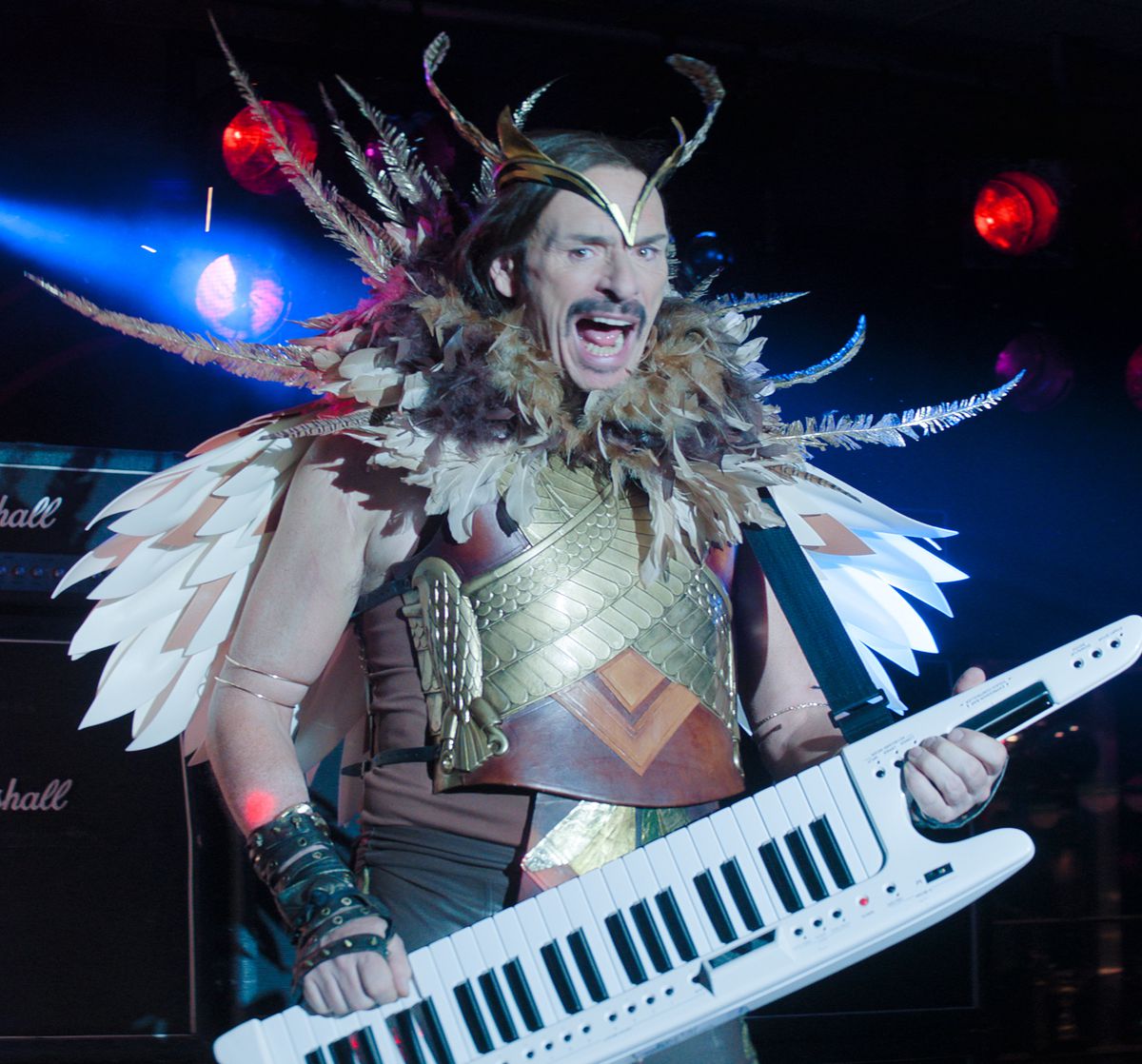 Julian Barrett playing a keytar while dressed as an owl in Knuckles