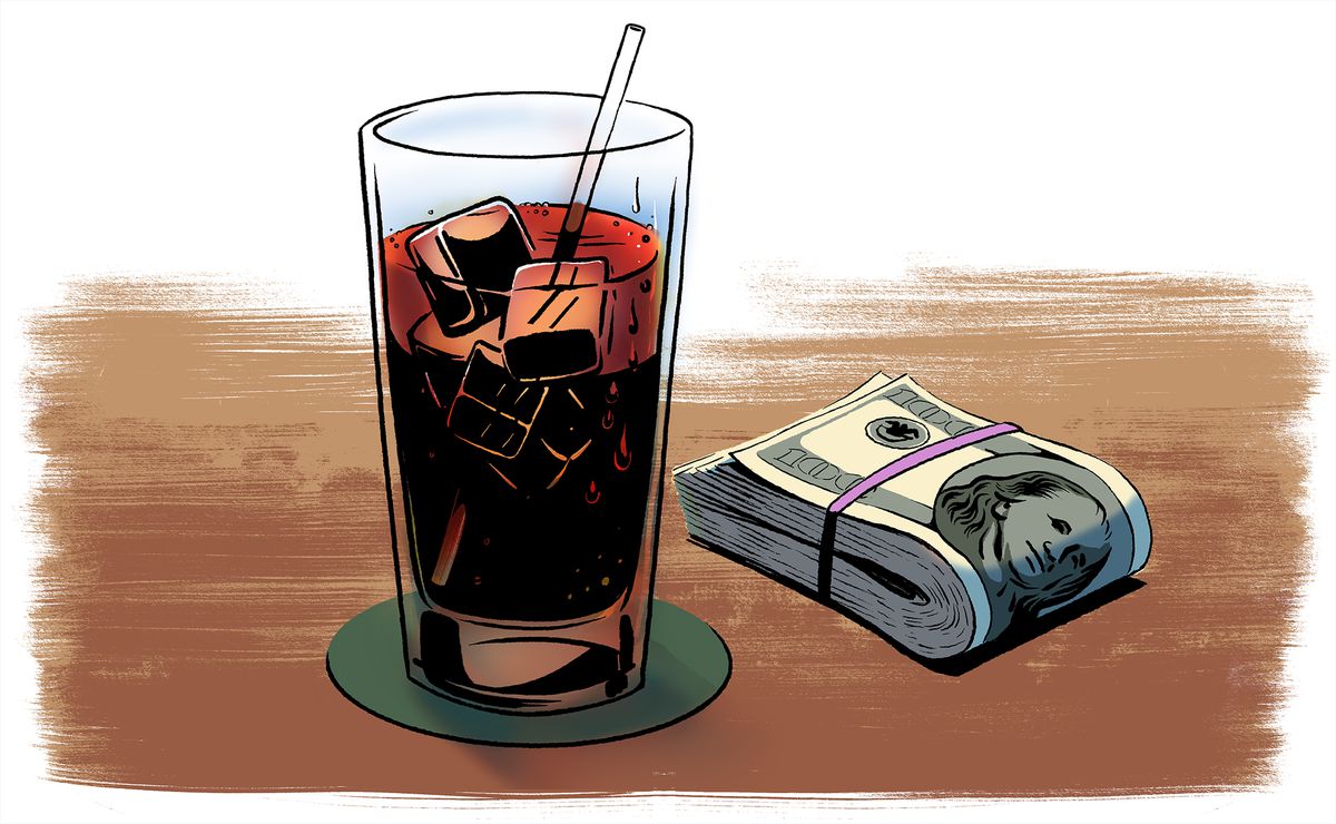 A tall cold glass of coke sits next to a large wad of cash.