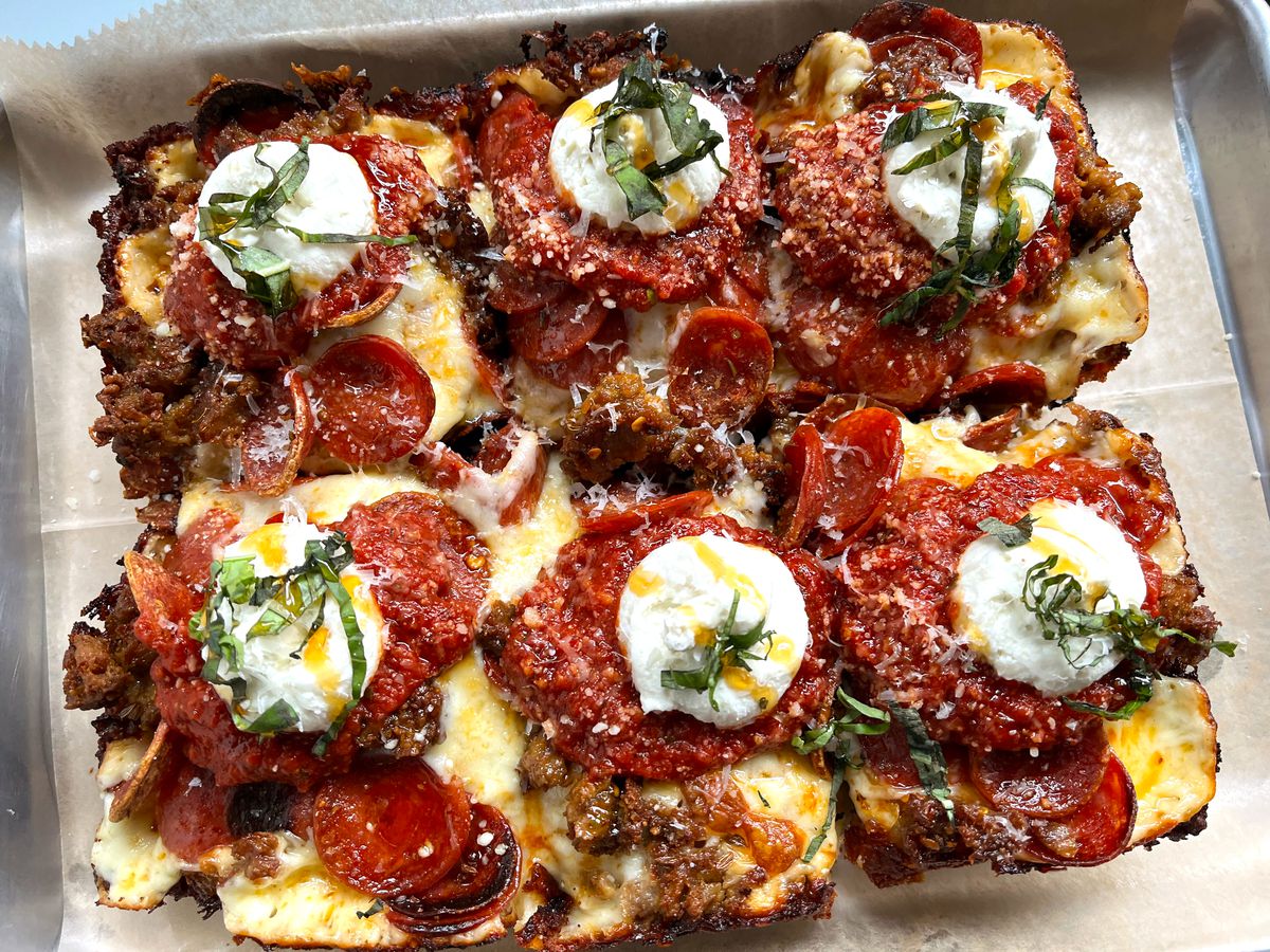 A rectangular pizza cut into six pieces, each topped with tomato sauce, pepperoni, and dollops of cheese.