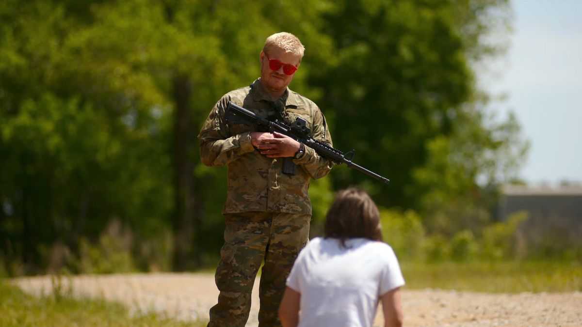 Actor Jesse Plemons, in military fatigues and holding an assault rifle, stands over a kneeling Cailee Spaeny in a still from A24 and Alex Garland’s Civil War